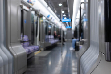 Blurred empty interior of a modern metro train, inside of an underground subway train with two unrecognizable people. Public transportation concept.