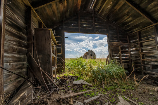 Abandoned barn interior with a view to another farm building; Val Marie, Saskatchewan, Canada