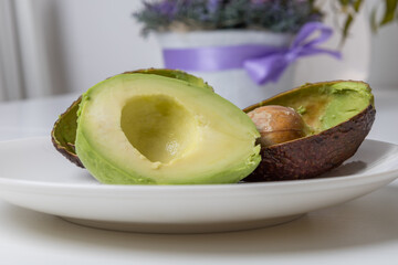 Avocado cut in half on a white plate. A seed in an avocado.