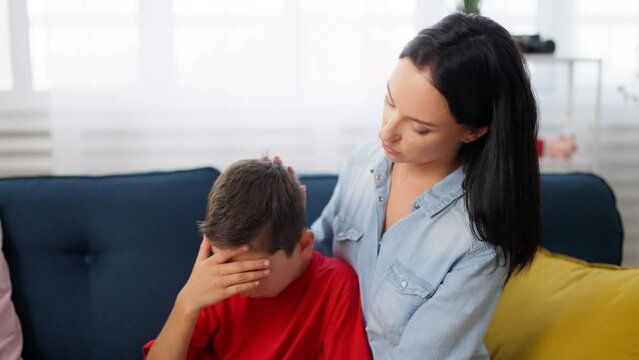 Schoolboy crying because of problems in school, mom hugging and comforting him