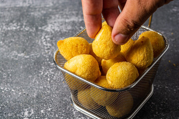 male hand picking up 'salgadinho de festa' or brazilian traditional party snack. a mix made of coxinha, bolinha de queijo and risolis. on a frying basket