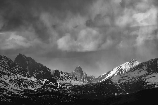 The jagged peaks of the Ogilvie Mountains with Tombstone Mountain in the center of the range under a cloudy sky along the Dempster Highway near Dawson City; Yukon, Canada