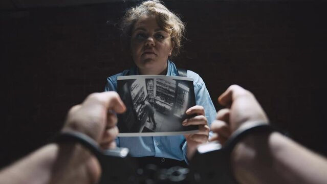 Lady interrogator with cigarette demonstrating photo evidence to suspect