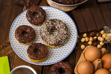 Preparing doughnuts at home. Ingredients for donuts such as eggs, milk, chocolate, pudding, butter, cacao, flour, rolling pin, cake pan, grater, egg beater, spatula