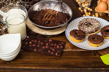 Preparing doughnuts at home. Ingredients for donuts such as eggs, milk, chocolate, pudding, butter, cacao, flour, rolling pin, cake pan, grater, egg beater, spatula
