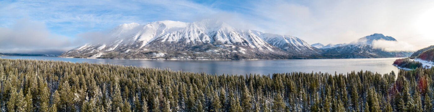 Panoramic aerial image of the beautiful landscape of Tutshi Lake with snow capped mountains in winter; Yukon, Canada
