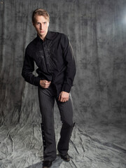 an attractive man in an elegant suit, shirt with embroidery. Photo in the studio on a gray...