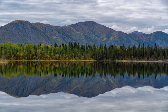 Beautiful reflection of the St. Cyr mountain range in Jackfish Lake; Ross River, Yukon, Canada