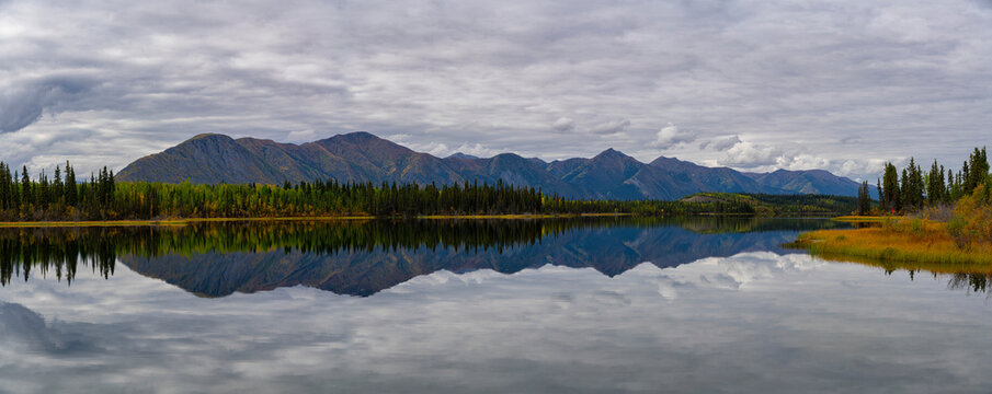 Beautiful reflection of the St. Cyr mountain range in Jackfish Lake; Ross River, Yukon, Canada
