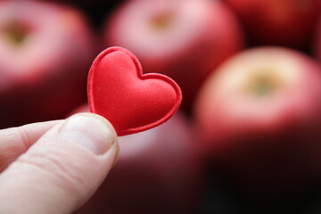 Fototapeta premium Hand holding a heart on the background of an apple healthy food concept.
