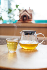 Close up of hot tea in a glass teapot on a table in a cafe.