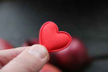 Hand holding a heart on the background of an apple healthy food concept.