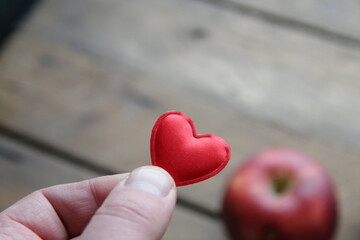 Obraz premium Hand holding a heart on the background of an apple healthy food concept.
