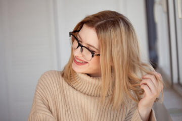 Young cute blonde with eyeglasses and a beige sweater. Stylish fashionable young woman. woman with glasses smiling - 552687830