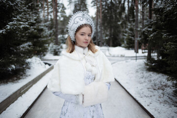 Snow Maiden , a cute young blonde in a white snow maiden costume with a kokoshnik , in the forest...