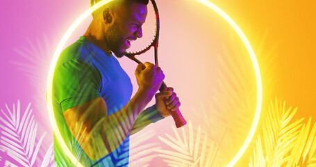 African american male tennis player holding racket screaming by illuminated circle and plants