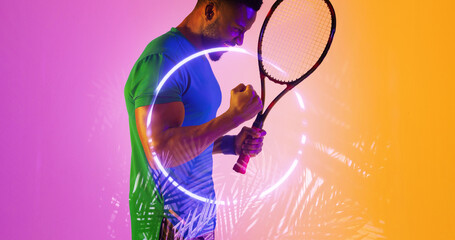Fototapeta na wymiar Side view of african american male player with racket shaking arms by illuminated plants and circle