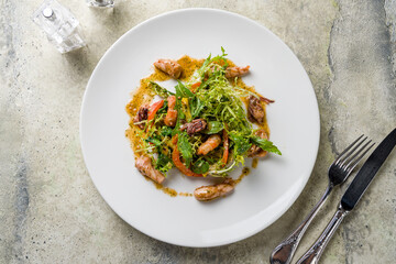Salad with seafood on white plate on stone table top view