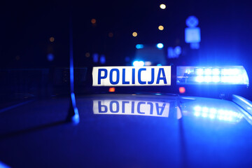 Radiowóz polska policja z Sygnalizator błyskowy niebieski na dachu radiowozu. Alarmowo wieczorem. - obrazy, fototapety, plakaty