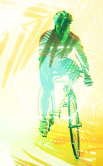 African american male cyclist riding bike with safety gear over illuminated yellow plants