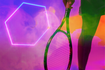 Midsection of african american male tennis player holding racket by illuminated hexagon