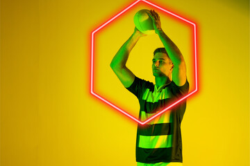 Caucasian male rugby player throwing ball by illuminated hexagon over yellow background