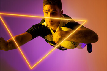 Caucasian male rugby player with ball jumping by illuminated triangle over gradient background