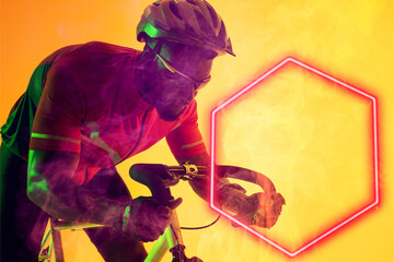 African american male cyclist wearing glasses and helmet riding bike by illuminated hexagon