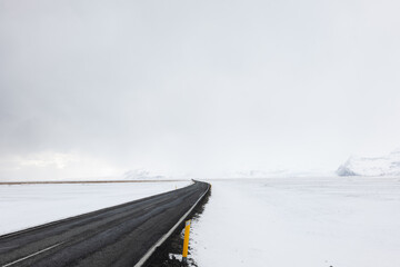 Obraz premium Road LEading Through the Frozen Snowy Landscape of Southern Iceland in Winter