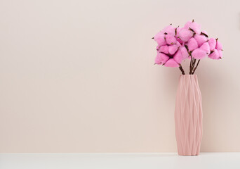 Pink ceramic vase with rose cotton bouquet on white table