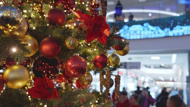 Christmas tree decorated with colorful glass balls inside large supermarkt fashion mall during winter holidays with customers shopping.