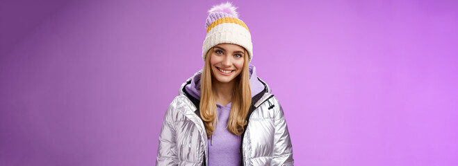 Cute young blond european woman wearing warm cozy jacket hat ski resort vacation having fun smiling amused rent equipment wanna learn snowboarding standing happily purple background - obrazy, fototapety, plakaty