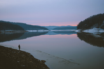 Person walking near Tygart Lake at sunrise in West Virginia, USA