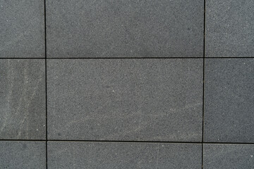 gray tile wall front view tiles in the shape of large rectangles texture and background of granite...