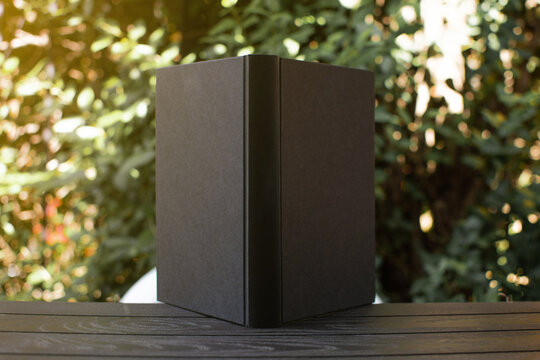 black book on wooden table outdoors