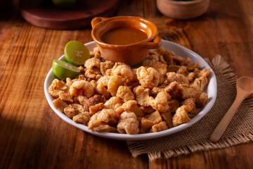 Chicharrones. Deep fried pork rinds, crispy pork skin pieces, traditional mexican ingredient or snack served with lemon juice and red hot chili sauce.
