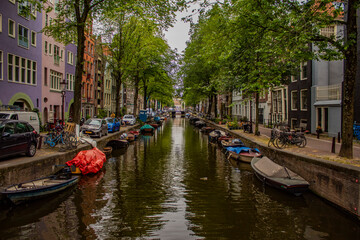 Fototapeta na wymiar A canal in Amsterdam, boats on the canal, parked cars, trees and historic buildings.