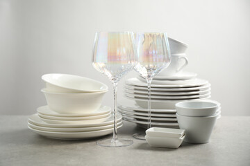 Set of clean dishes and glasses on light grey table