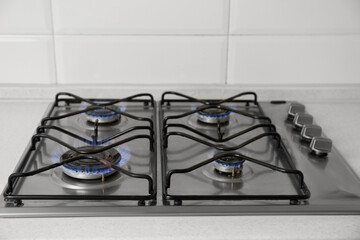 Gas cooktop with burning blue flames in kitchen