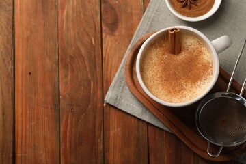 Delicious eggnog with anise and cinnamon on wooden table, top view. Space for text