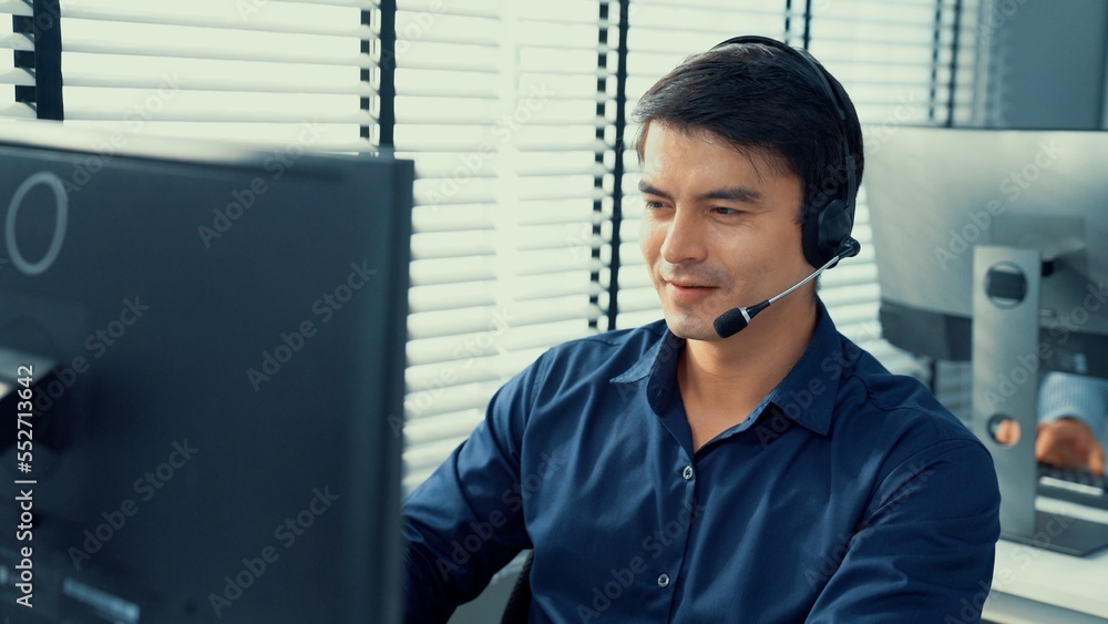 Aufkleber young competent asian male call center agent working at his computer while simultaneously speaking w