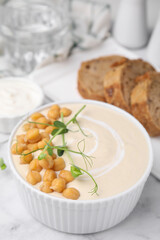 Tasty chickpea soup in bowl on white marble table
