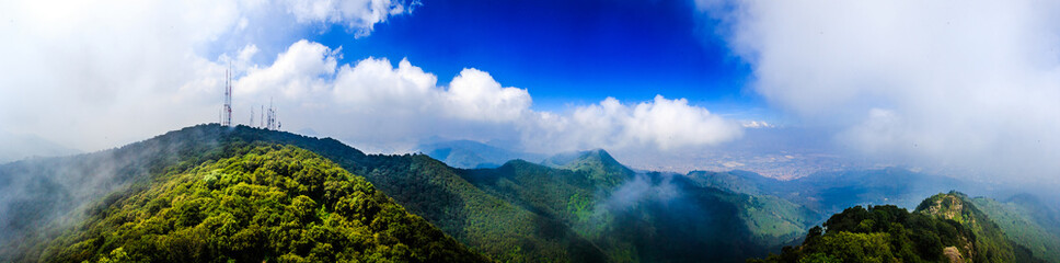 mountain top surrounded by white clouds with green hills and anthens of tv, sierra de guadalupe state of mexico and mexico city 