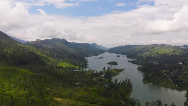 Aerial view of lake in the mountains surrounded by hills with tea plantations. Maskeliya, Castlereigh, Sri Lanka.