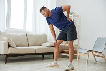 Man backache neck and shoulder pain, inflammation of muscles and ligaments rupture during sports, inflammation and injury, in a blue t-shirt at home