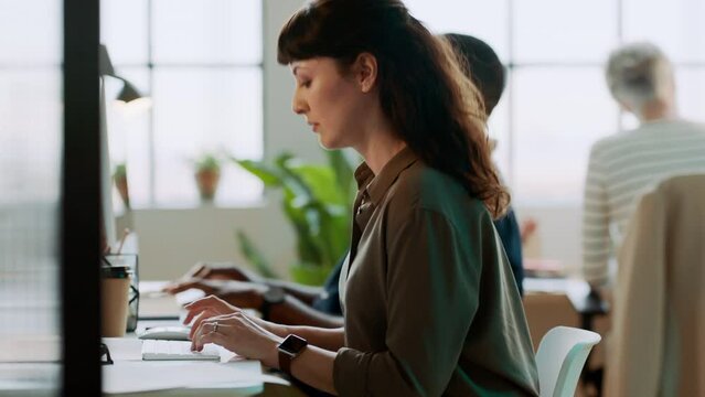 Office, business people and woman typing on computer writing an email, proposal or project. Company, coworking and busy staff, employees and businesswoman working on pc at desk in modern workplace.