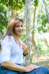 Asian woman wearing white shirt with trees background