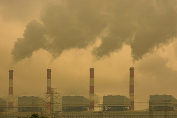 Cropped shot of coal power plant with steam pouring out of the stack. Industrial smoke stack of coal power plant in the morning.