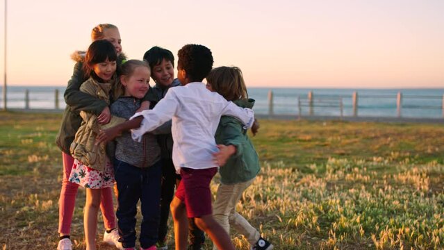 Hug, holiday and friends at a park with support, love and care during summer together. Diversity, nature and children with affection, smile and solidarity on a vacation on a field by the ocean