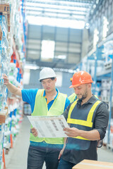 Warehouse workers in helmets checking goods and supplies on shelves with goods background in warehouse worker packing in a large warehouse in a large warehouse. Logistics industry concept..